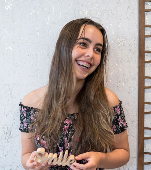 Teen-treatment-horton-ortho Girl smiling with smile sign in hand braces
