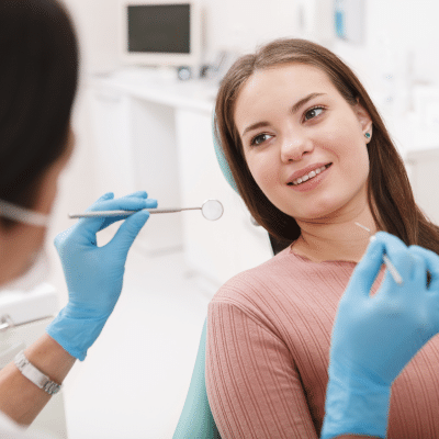 Your first orthodontic consultation: what to expect 4 A woman sitting in a dental chair while orthodontist talks to her holding a dental tool, representing first orthodontic consultation
