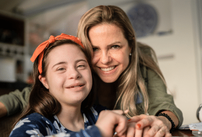 The benefits of inclusive orthodontic care 3 Smiling woman and special needs girl at desk, representing the benefits of inclusive orthodontic care