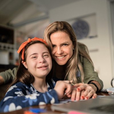 The benefits of inclusive orthodontic care 3 Smiling woman and special needs girl at desk, representing the benefits of inclusive orthodontic care